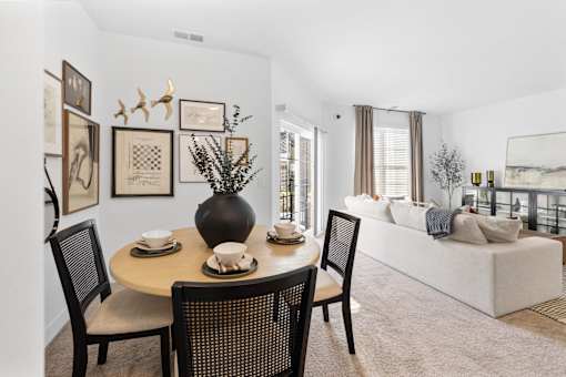 A dining room with a table set for two and a couch in the background.
