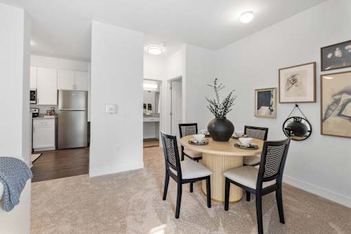 A dining room with a table set for two and a vase on the table.