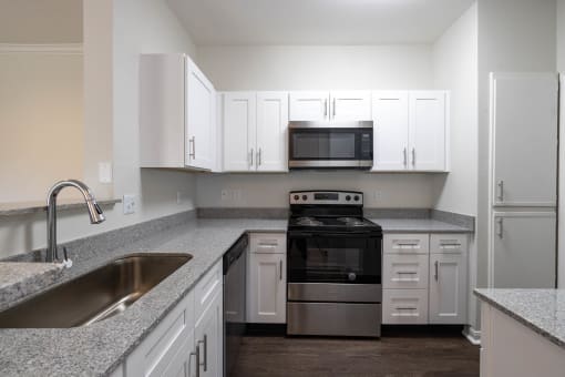 Renovated kitchen featuring black appliances and granite counters at Center Point Apartments, Indianapolis