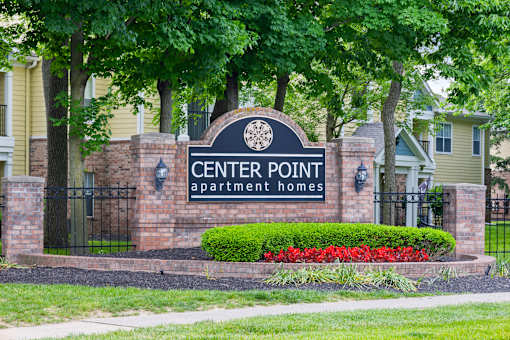Leasing signage for Center Point Apartment Homes set against a brick entrance with vibrant landscaping and mature trees.