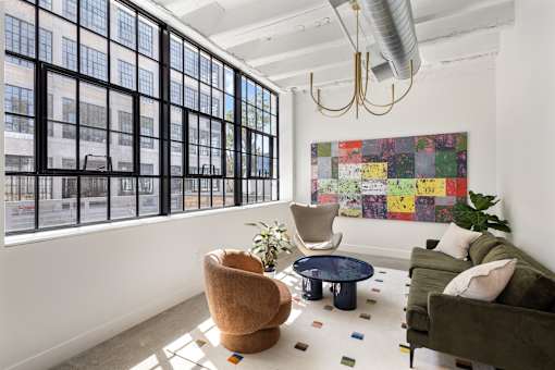 Leasing Center lounge seating beneath a wall of original steel factory windows