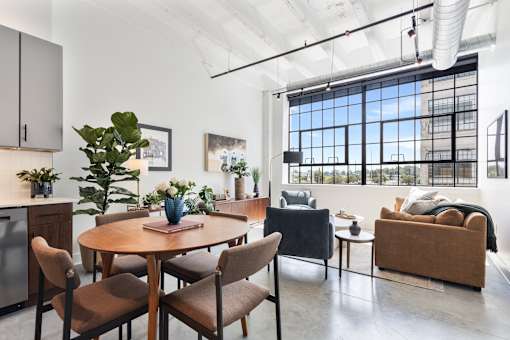 Open loft living room and kitchen with a wall of steel factory windows at Cole Motor in Indianapolis