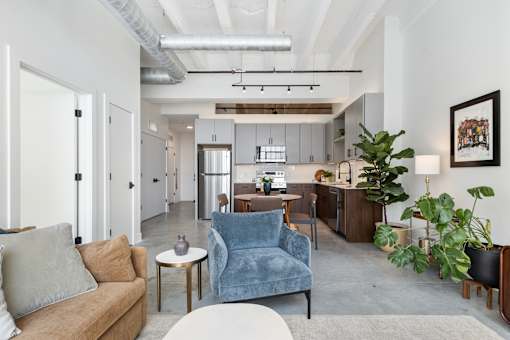 Open-concept loft living and kitchen with exposed ductwork and track lighting
