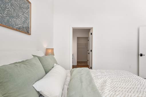 Bedroom with an open walk-in closet door and framed art