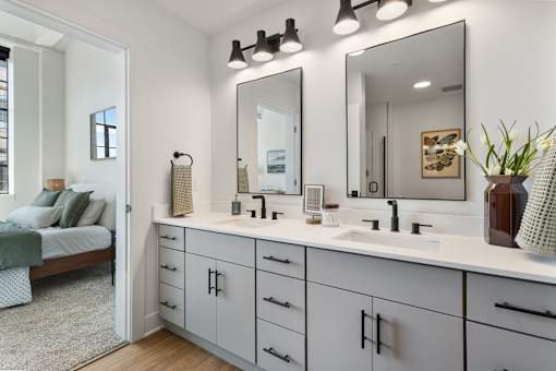 Primary bathroom with double vanity, two mirrors and a view into the bedroom