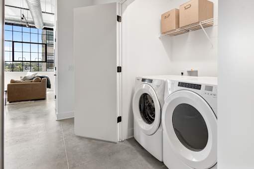 In-unit laundry closet with shelving, washer and dryer