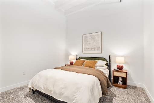 Second bedroom in a two bedroom loft with spindle bed and warm linens
