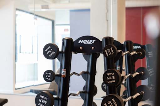 Close-up of HOIST fixed-weight barbells in the Cole Motor Apartments fitness center in Indianapolis, displayed in front of a mirrored wall.