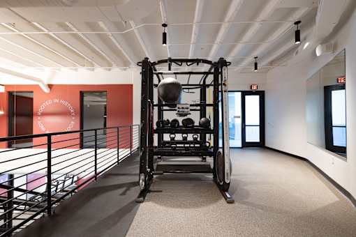 Upper-level workout area at Cole Motor Apartments in Indianapolis featuring a functional training station, kettlebells, medicine balls, and industrial-style ceilings.