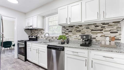 an open kitchen with white cabinets and a counter top at Elea Apartments in Marietta, GA
