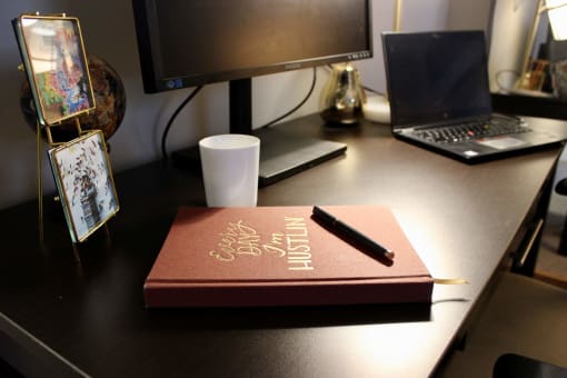 a book on a desk with a pen and a cup