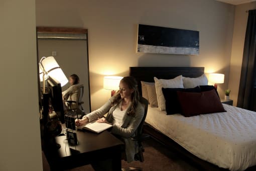 a woman sits at a desk in a hotel room