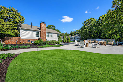 A sunny day at a park with a green lawn and a white building.