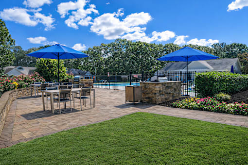 A patio with a table and chairs under blue umbrellas.