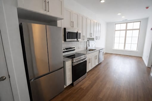 A modern kitchen with stainless steel appliances and wooden floors.