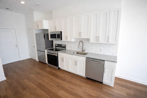 A kitchen with white cabinets and a wooden floor.