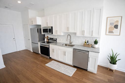 A kitchen with white cabinets and a wooden floor.
