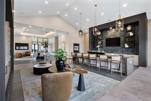 Resident lounge and clubroom at Montage West Lafayette featuring bar seating, modern lighting, cozy seating areas, and an open-concept design.