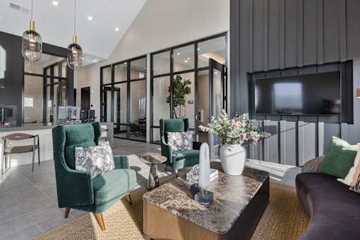 Resident lounge at Montage West Lafayette featuring modern seating, mounted TV, and adjacent coworking spaces with glass walls.