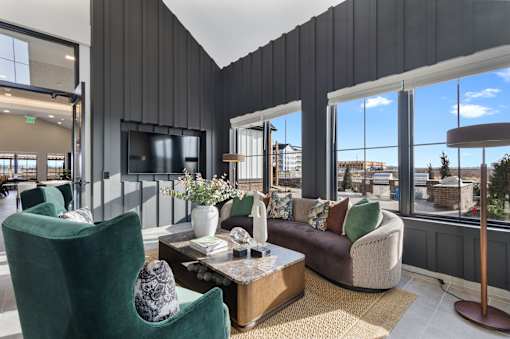 Resident lounge at Montage West Lafayette featuring modern seating, mounted TV, and adjacent coworking spaces with glass walls.