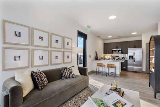 A modern living room with a grey couch and a coffee table in front of a wall with framed pictures.