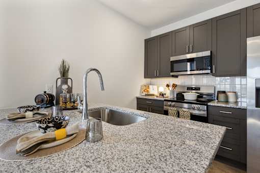 Modern apartment kitchen at Montage West Lafayette with granite countertops, stainless steel appliances, and large center island.