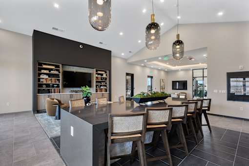 Community bar and lounge area with oversized island seating, pendant lighting, built-in shelving, and modern finishes at Montage apartment community