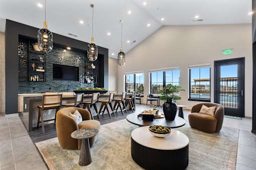 Spacious resident lounge with bar seating, pendant lighting, modern fireplace wall, and pool views at Montage apartment community