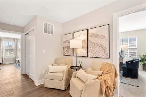 Inviting seating area in single-family rental home at Mural Lewis Center featuring neutral tones, accent chairs, wall art, wood-style flooring, and warm natural light