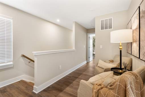 Interior staircase at Mural Lewis Center featuring wood-style flooring, white railing, neutral walls, and open layout leading to upper-level living space