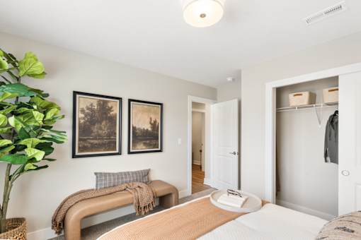 Stylish apartment bedroom at Mural Lewis Center featuring neutral tones, ceiling fan, large window, framed wall art, and modern furnishings with natural light