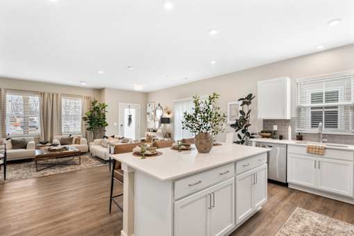 Modern kitchen in single-family rental home at Mural Lewis Center featuring large island with seating, white cabinetry, stainless steel appliances, quartz countertops, and open-concept design