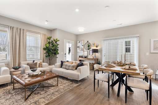 Spacious open-concept living and dining area at Mural Lewis Center featuring wood-style flooring, neutral tones, large windows, modern furnishings, and seamless flow into the kitchen