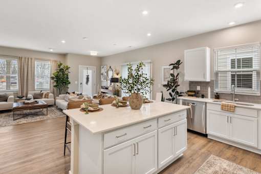 Modern apartment kitchen at Mural Lewis Center featuring large island with quartz countertops, white cabinetry, stainless steel appliances, wood-style flooring, and open-concept design
