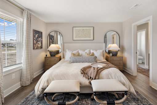 Primary bedroom at Mural Brownsburg rental home featuring neutral color palette, plush carpeting, and modern staging with bedside lighting