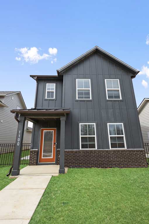 Craftsman-style rental home with covered front porch and green siding at Mural Lewis Center