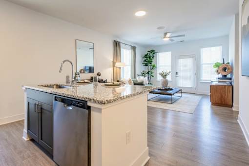 Open-concept kitchen with granite island and view into living room at Nook Nine