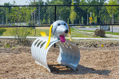 A metal sculpture of a dog with a yellow ribbon around its neck.