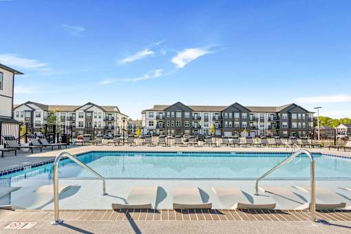 Apartment community pool with in-water loungers and surrounding buildings at Nook Nine