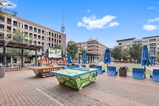 A sunny day in a city square with a green and yellow table in the center.