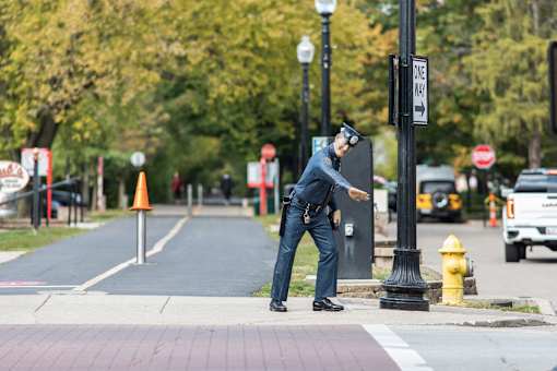 a police officer is standing on the curb of a street at Gramercy Apartments, Indiana, 46032