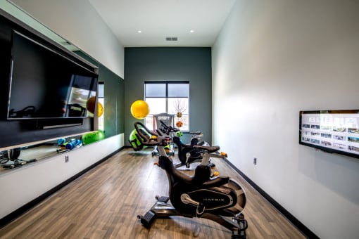 a home gym with exercise machines and a large screen tvat The Century at Purdue Research Park-Student, West Lafayette Indiana