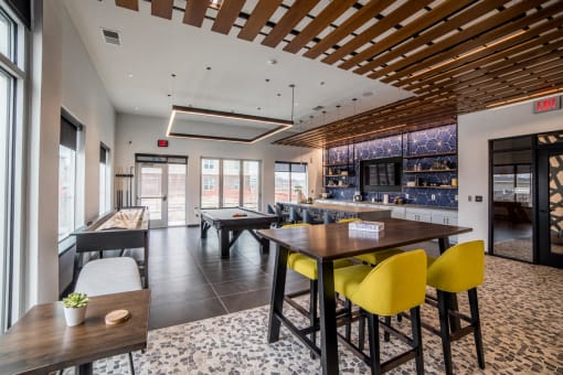 a clubhouse with a bar and tables with chairs at The Century at Purdue Research Park-Student, West Lafayette, IN