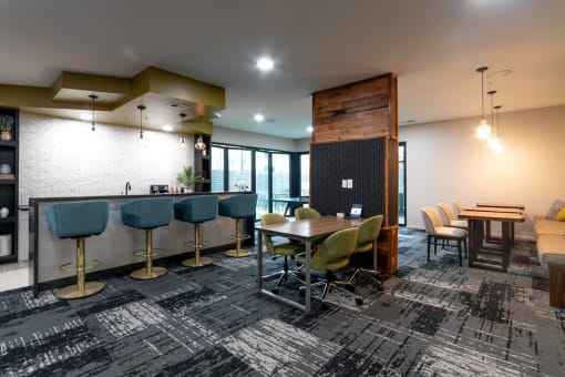 a lounge area with tables and chairs and a bar with stools at 310 at Nulu Apartments-Student, Louisville, 40202
