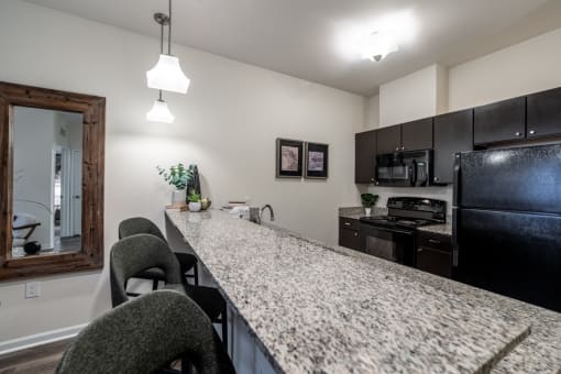 view of kitchen with granite counter top and black appliances at the preserve at greatstone at 310 at Nulu Apartments-Student, Louisville Kentucky