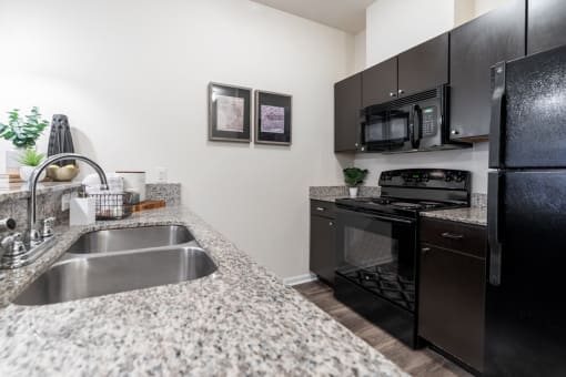a kitchen with granite counter tops and black appliances at 310 at Nulu Apartments-Student, Kentucky, 40202
