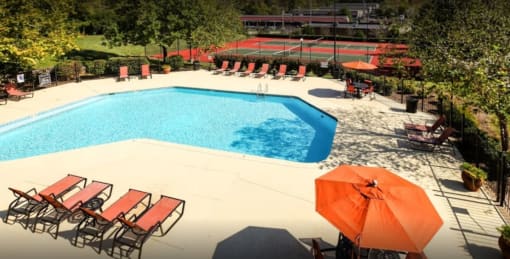 a swimming pool with chairs and an umbrella in a garden at Landmark at Lyncrest Reserve Apartments, Nashville, TN, 37209