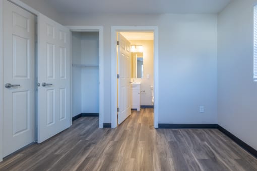 an empty room with white doors and a bathroom in the background