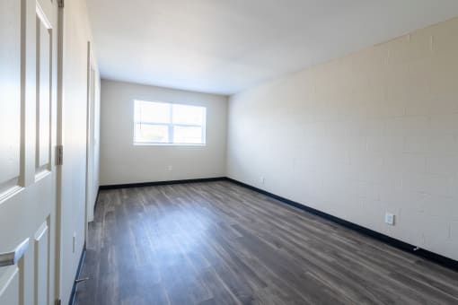 the living room of an empty apartment with wood flooring and a window