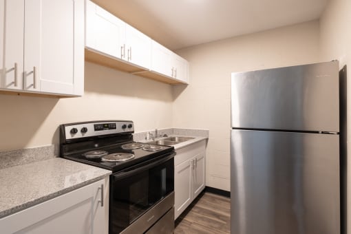 a kitchen with white cabinets and stainless steel appliances and a refrigerator